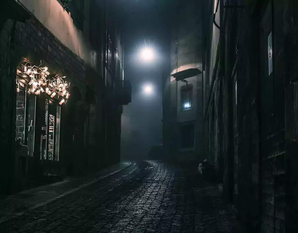 Old European narrow empty street of a medieval town on a foggy evening.